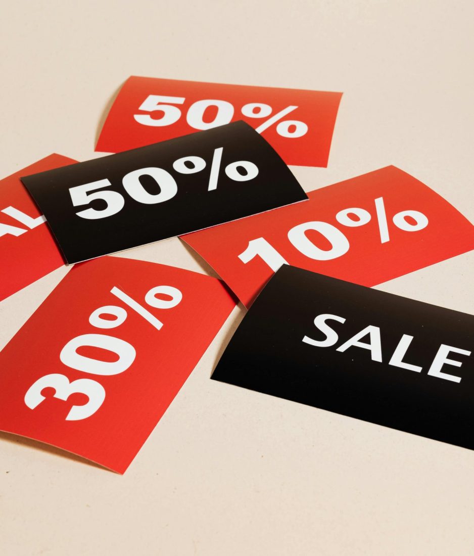 Red and black sale tags showing various discount percentages on a beige background.